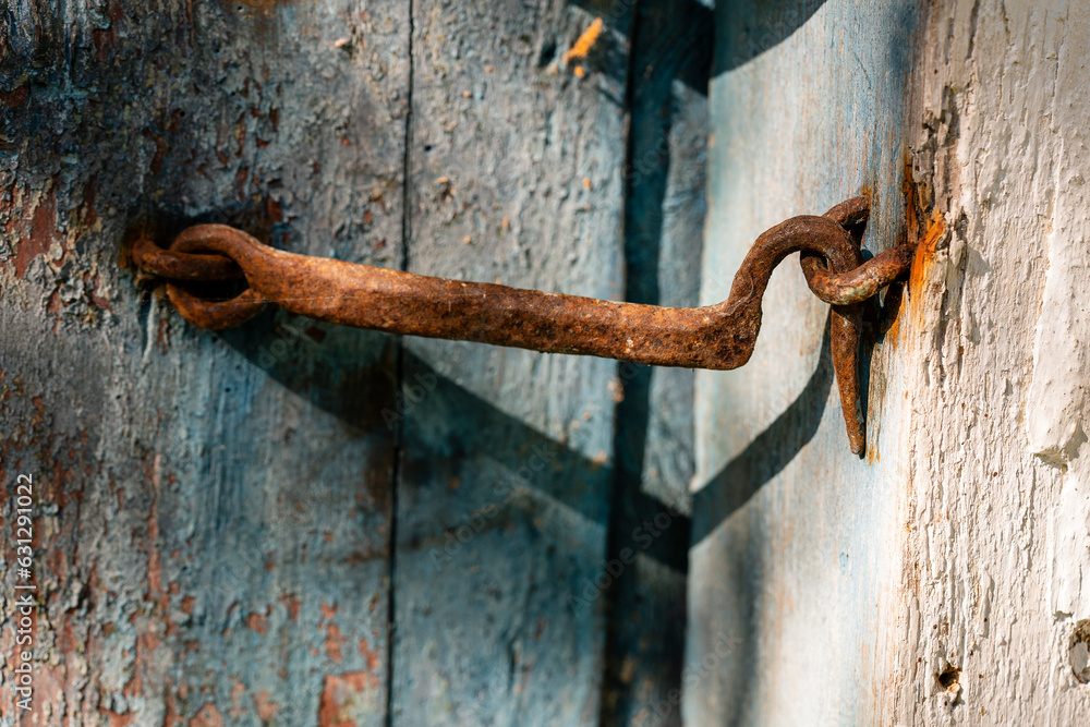 Very rusty door hook closing a wooden door, closeup. An old wooden gate ...