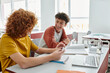 © LIGHTFIELD STUDIOS - Cheerful schoolboy talking to friend while using digital tablet near notebooks on desk in classroom