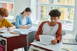 © LIGHTFIELD STUDIOS - Teenage schoolboy using digital tablet near devices with blank screen and classmates in classroom