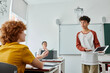 © LIGHTFIELD STUDIOS - Teen schoolboy pointing at digital tablet with blank screen near classmate during lesson in class