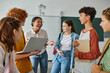 © LIGHTFIELD STUDIOS - cheerful african american teacher laughing with teenage students in classroom, back to school
