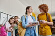 © LIGHTFIELD STUDIOS - happy teenage boy and girl holding gadgets near classmates in school hallway, back to school concept