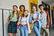 © LIGHTFIELD STUDIOS - teenage schoolkids looking at camera and standing in school hallway, teen classmates with devices
