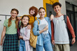 © LIGHTFIELD STUDIOS - back to school, happy teenagers looking at camera in hallway, holding devices and smiling together