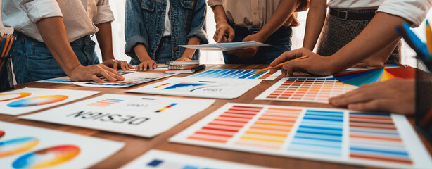 Wall Mural - Graphic designer brainstorm logo and graphic art at busy creative studio workshop. Experiment and brainstorm color palette and pattern at workspace table for creative design. Panorama shot. Scrutinize