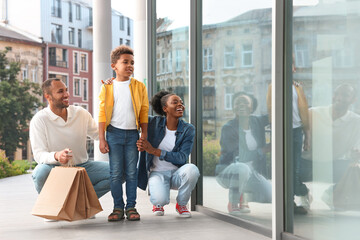 Wall Mural - Family shopping. Happy parents and son with purchases near mall outdoors