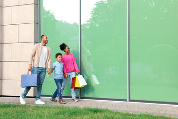 Wall Mural - Family shopping. Happy parents and son with colorful bags near mall outdoors