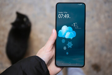 Wall Mural - woman checking weather using app on smartphone outdoors, closeup. data and illustration of cloud wit