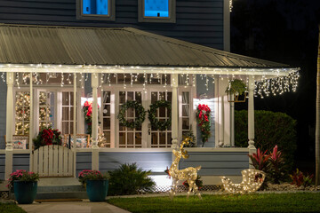 Brightly illuminated christmas decorations on front yard porch of florida family home. Outside decor for winter holidays