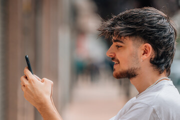 portrait of young man in the street looking at the mobile phone