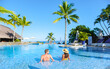 © Fokke Baarssen - Man and Woman relaxing in a swimming pool, a couple on a honeymoon vacation in Mauritius tanning in the pool with palm trees and sun beds