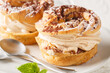 Classic French cake Paris Brest from choux pastry with cream decorated with powdered sugar and cocoa close-up in a plate on the table. Horizontal