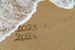 Bonne et heureuse année 2024, élégante carte de voeu montrant la fin de 2023 et le passage à 2024 sur le sable d'une plage