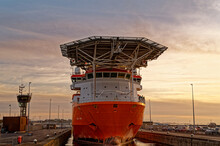 A Huge Merchant Sea Vessel In The Port Lock Against The Sky At Sunset