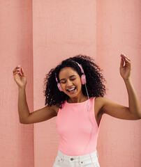 Happy woman wearing pink headphones enjoying music with closed eyes