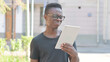 © stockbakers - Young African Man Upset by Loss on Tablet Outdoor