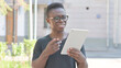 © stockbakers - Young African Man Doing Video Chat on Tablet Outdoor