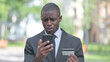 African Businessman Upset by Online Payment Failure on Phone Outdoor