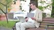 Casual Young Man Feeling Upset while Reading Contract and Using Laptop Outdoor