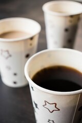 Sticker - Close-up shot of two ceramic coffee cups sitting on a black table with a star pattern