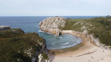 Sticker - Tranquil beach in Asturias, Spain, surrounded by lush greenery and dramatic cliffs