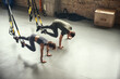 © Friends Stock - Young and sporty. Top view of a couple in sportswear training with Trx fitness straps at gym