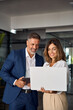 © Stock 4 You - Vertical portrait of mature Latin business man and European business woman discussing project on laptop in office. Two diverse confident professional partners colleagues business people work together.
