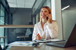© Kostiantyn - Woman sales manager talking by phone with client sitting in modern coworking and working on laptop