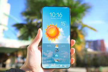 Wall Mural - man using weather forecast app on smartphone outdoors on sunny day, closeup. data, sun and other ill