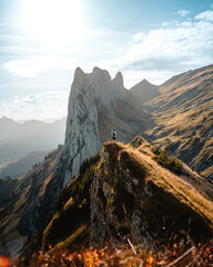 Tiny person in front of the Huge mountains in the Appenzeller region, Saxer Lücke, during a beautiful and colorful autumnal day. Hiking and active photography concept