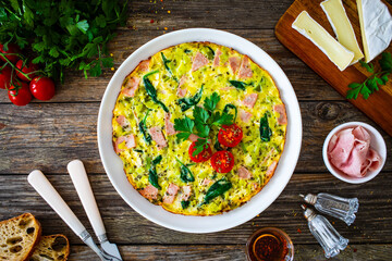Canvas Print - Delicious breakfast - egg omelette with mortadella, leek,spinach and cherry tomatoes on wooden table
