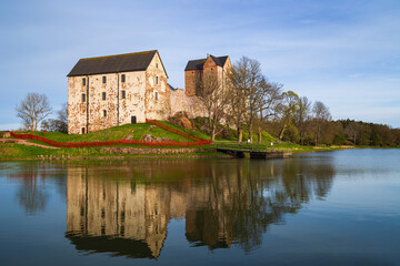 Wall Mural - Medieval Kastelholm Castle and its reflections on a calm river in Åland Islands, Finland, on a sunny day in the summer.