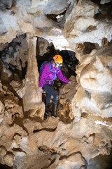 Wall Mural - Young woman spelunking inside a cave. Feminism concept. Concept of women's sport.