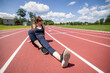 © Cavan Images - woman sits and relaxes on a running track while working out