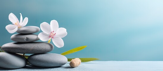 a tranquil spa and wellness concept with a pile of zen stones, flowers, and towels placed on a light