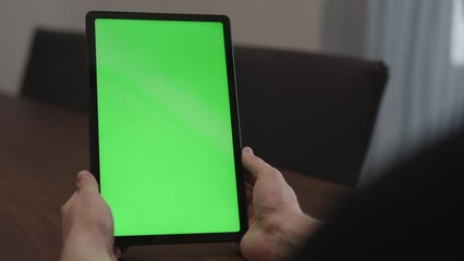 Sticker - Man at home using tablet pc with green screen while sitting at the table