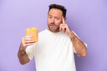 Wall Mural - Middle age caucasian man holding fried chips isolated on purple bakcground thinking an idea