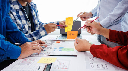 Close-up ux developers and ui designers use augmented reality to brainstorm on mobile app interface wireframe designs on modern office desks. Creative digital development office