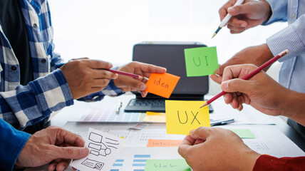 Close-up ux developers and ui designers use augmented reality to brainstorm on mobile app interface wireframe designs on modern office desks. Creative digital development office