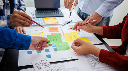 Close-up ux developers and ui designers use augmented reality to brainstorm on mobile app interface wireframe designs on modern office desks. Creative digital development office