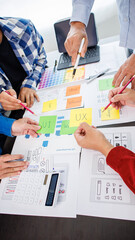 Close-up ux developers and ui designers use augmented reality to brainstorm on mobile app interface wireframe designs on modern office desks. Creative digital development office