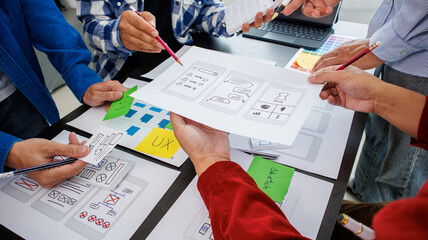 Close-up ux developers and ui designers use augmented reality to brainstorm on mobile app interface wireframe designs on modern office desks. Creative digital development office