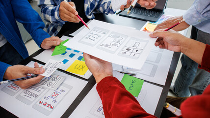 Close-up ux developers and ui designers use augmented reality to brainstorm on mobile app interface wireframe designs on modern office desks. Creative digital development office