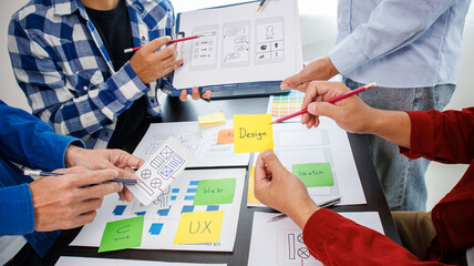 Close-up ux developers and ui designers use augmented reality to brainstorm on mobile app interface wireframe designs on modern office desks. Creative digital development office