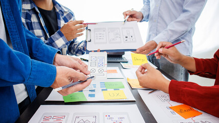 Close-up ux developers and ui designers use augmented reality to brainstorm on mobile app interface wireframe designs on modern office desks. Creative digital development office