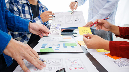 Close-up ux developers and ui designers use augmented reality to brainstorm on mobile app interface wireframe designs on modern office desks. Creative digital development office