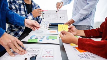 Close-up ux developers and ui designers use augmented reality to brainstorm on mobile app interface wireframe designs on modern office desks. Creative digital development office