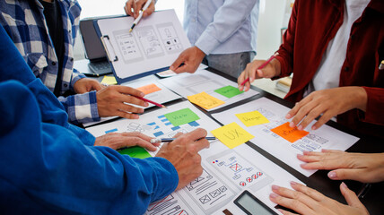 Close-up ux developers and ui designers use augmented reality to brainstorm on mobile app interface wireframe designs on modern office desks. Creative digital development office