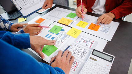 Close-up ux developers and ui designers use augmented reality to brainstorm on mobile app interface wireframe designs on modern office desks. Creative digital development office