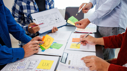 Close-up ux developers and ui designers use augmented reality to brainstorm on mobile app interface wireframe designs on modern office desks. Creative digital development office
